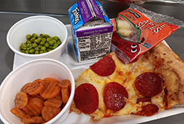  Pizza, peas, carrots, apple slices, chocolate milk on a tray